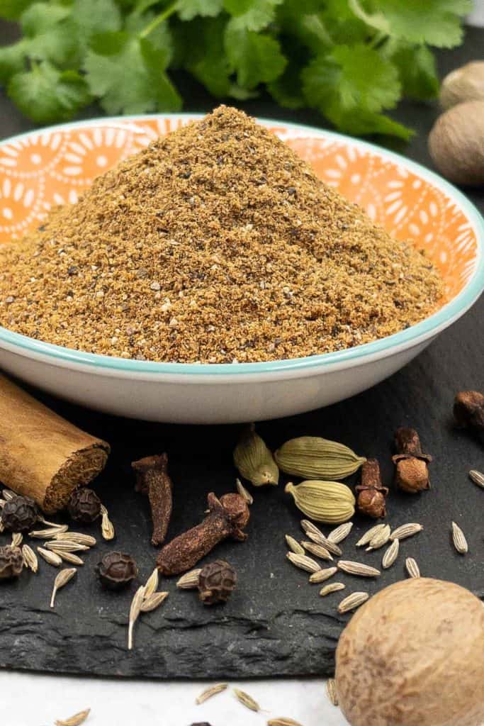 Garam masala spice blend with whole spices surrounding it.