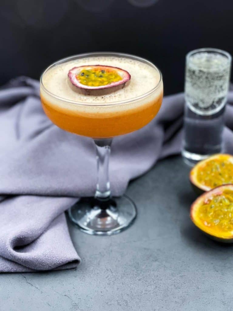 A passion fruit martini with a fizzy shot of sparkling wine and passion fruit halves.