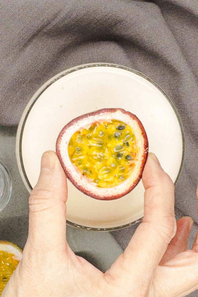 Placing a passion fruit half on the top of the passion fruit martini.