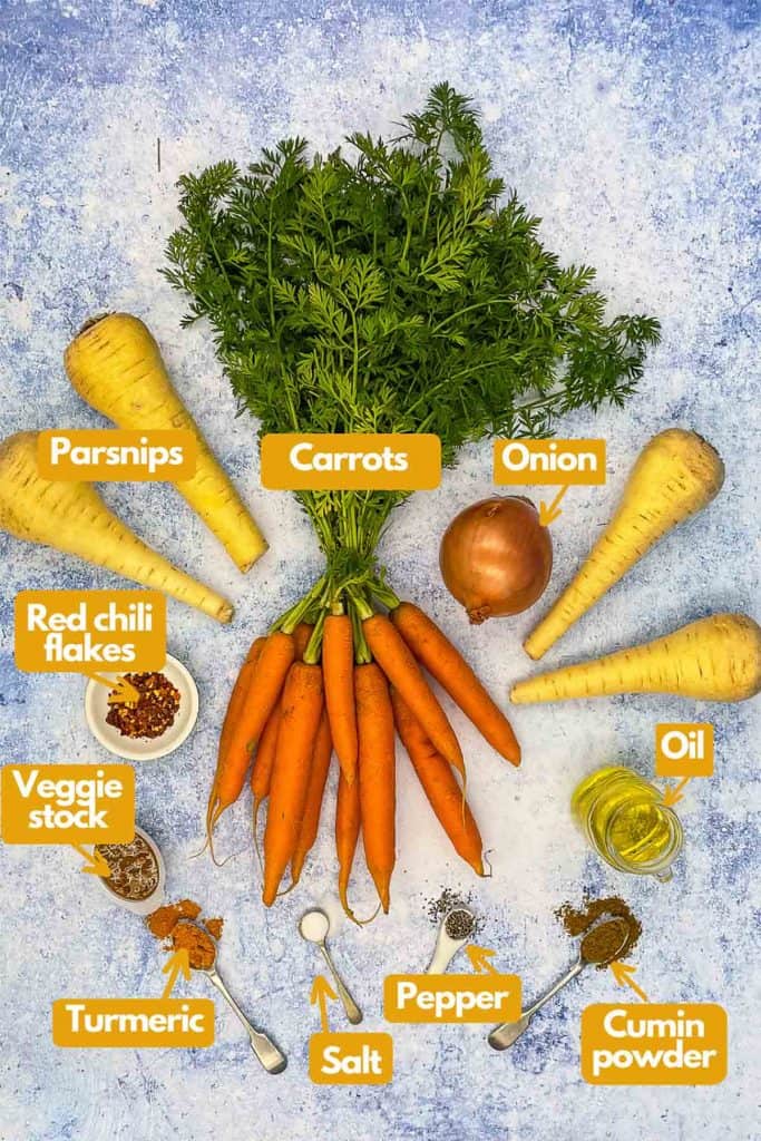 Ingredients needed for carrot parsnip soup; parsnips, carrots, onion, oil, cumin powder, black pepper, kosher salt, turmeric, vegetable stock, and red chili flakes.