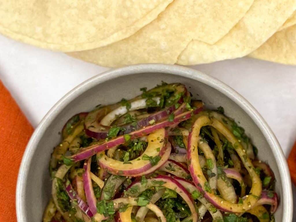 Thinly sliced red onions in an Indian dressing, and poppadoms to the side.