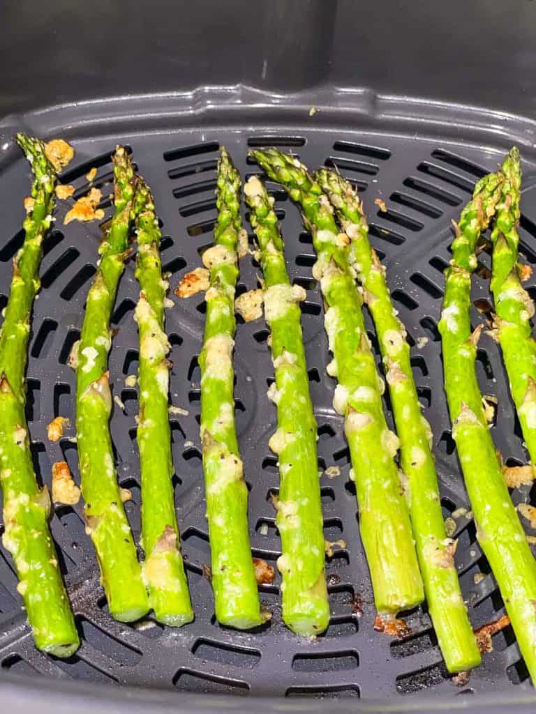 Cooked asparagus in an air fryer basket.
