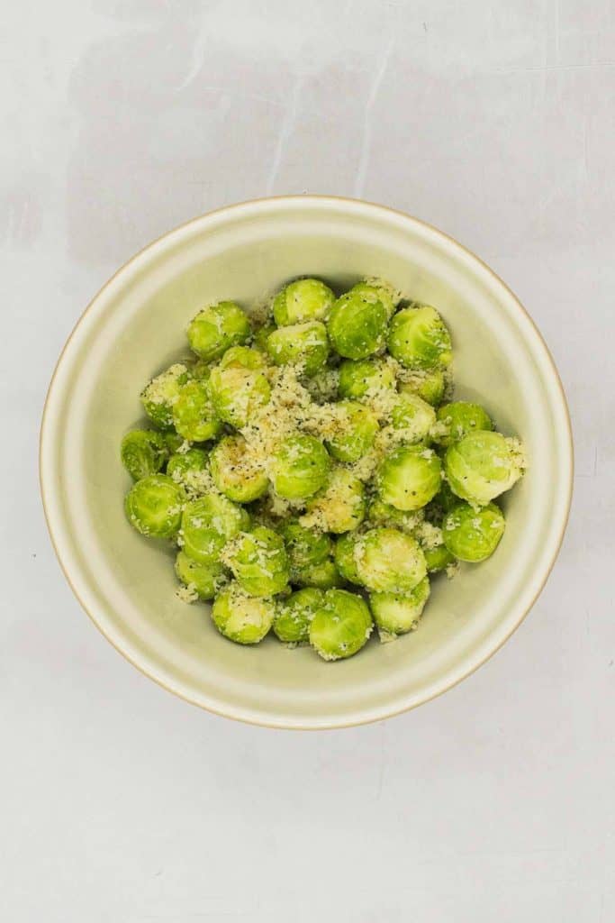 Place your Brussels sprouts in bowl, add extra virgin olive oil, maple syrup, vegetarian Parmesan cheese, kosher salt, ground black pepper, and toss.