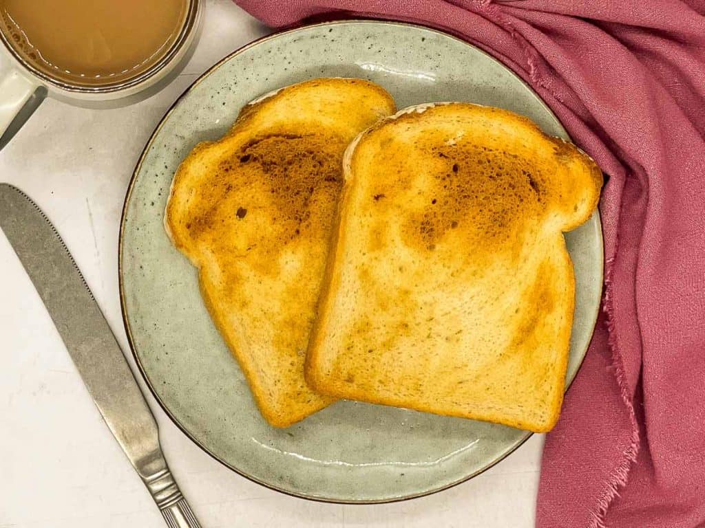 Two slices of golden brown air fryer toast on a plate.