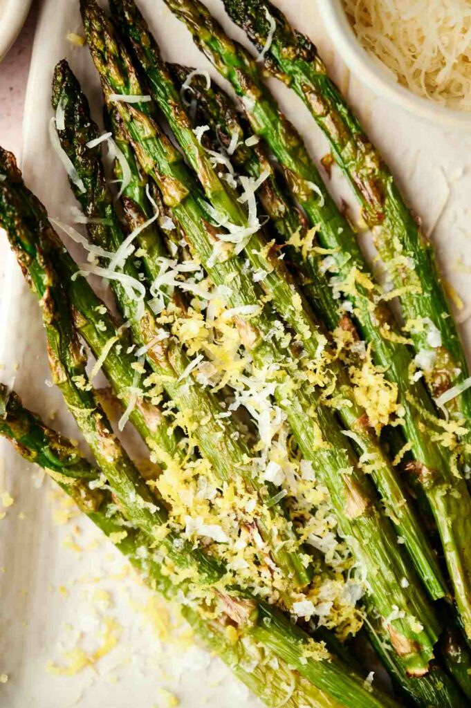 Air-fried asparagus with lemon and parmesan on a white plate.