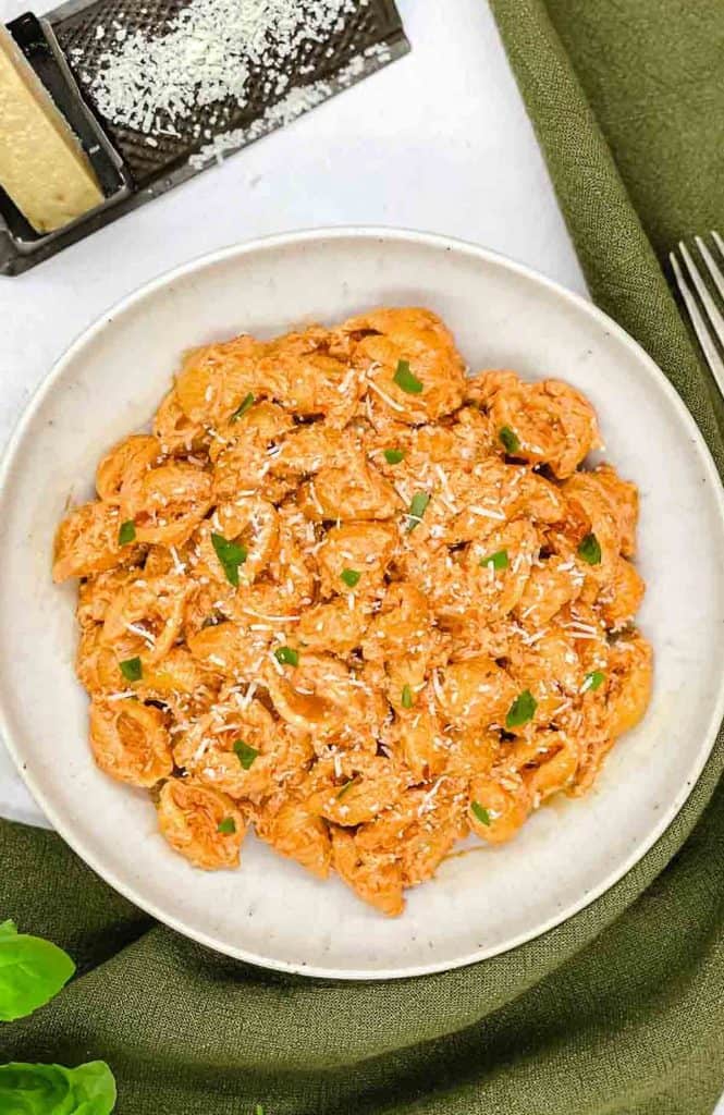 A bowl of Gigi Hadid pasta with a fork and cheese grate by the side.