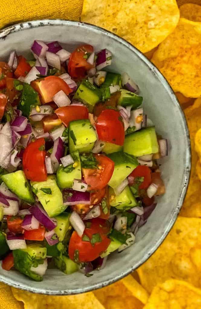 Delicious summer salad in a bowl, with poppadoms surrounding it.
