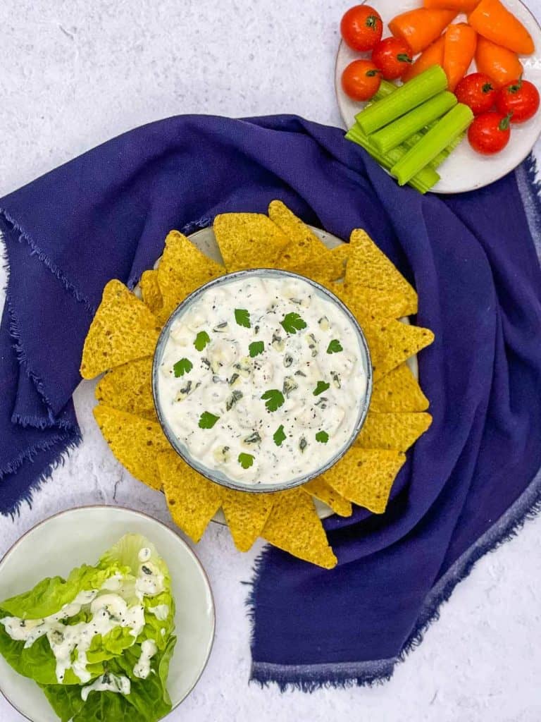 Blue cheese dressing with plates of fresh vegetables.