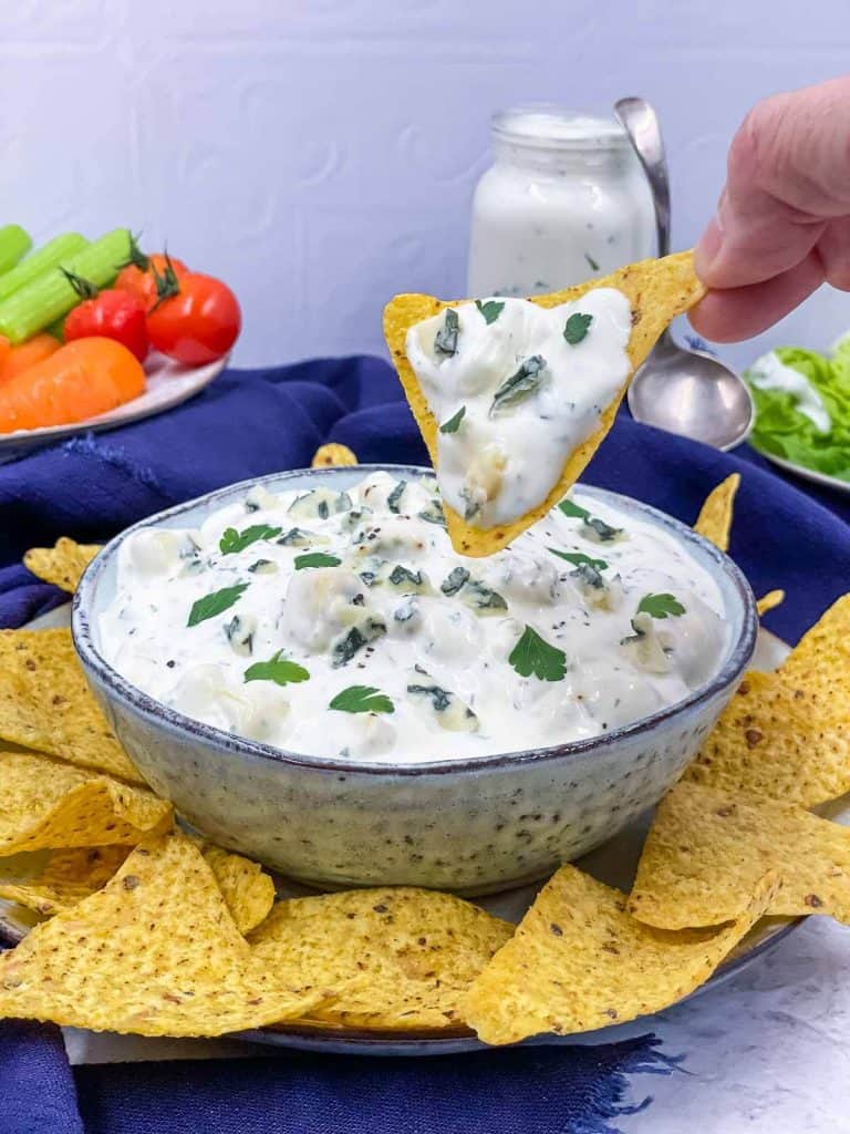Someone dipping a tortilla in blue cheese dip.