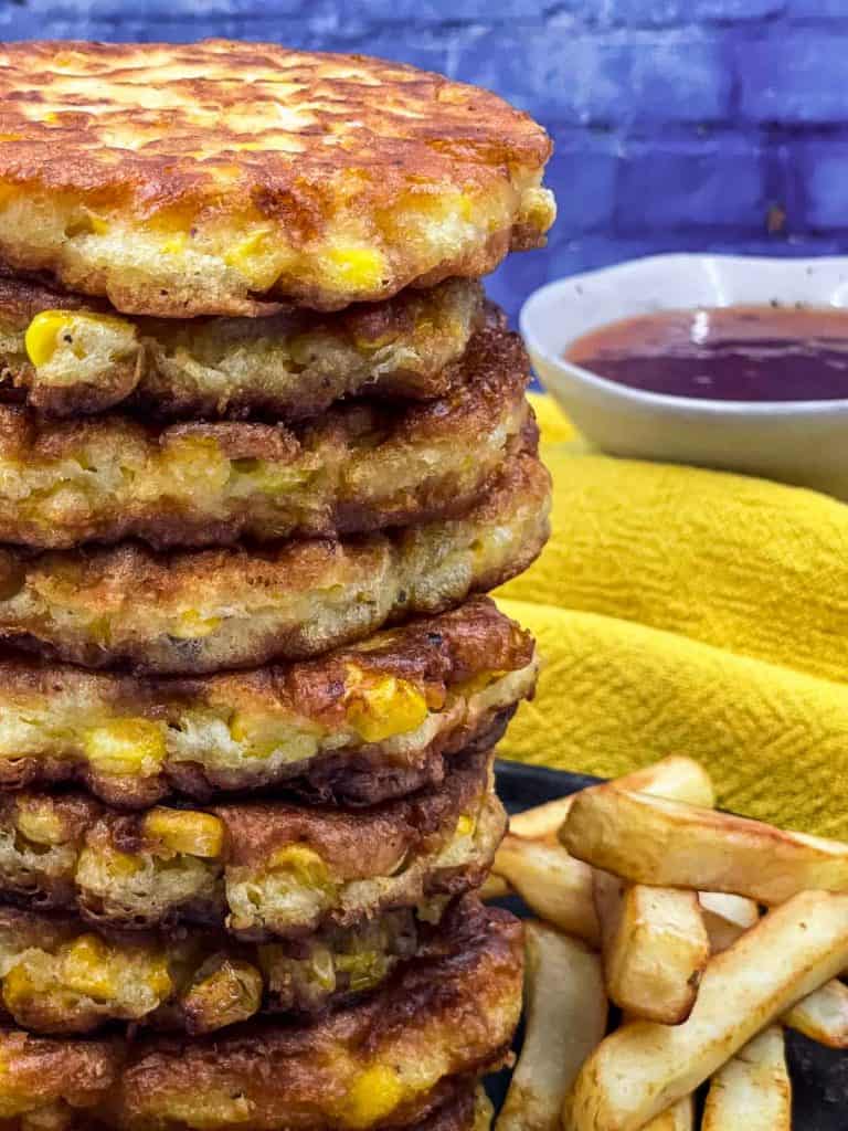 Stack of corn fritters, French fries and dipping sauce.