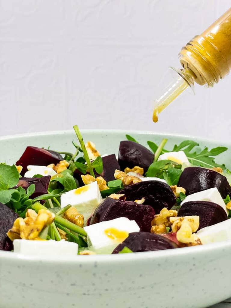 Drizzling balsamic vinaigrette over a beetroot salad.