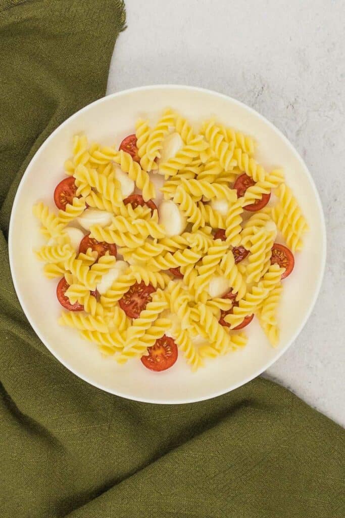 Pasta, mozzarella balls, and cherry tomatoes in a bowl.