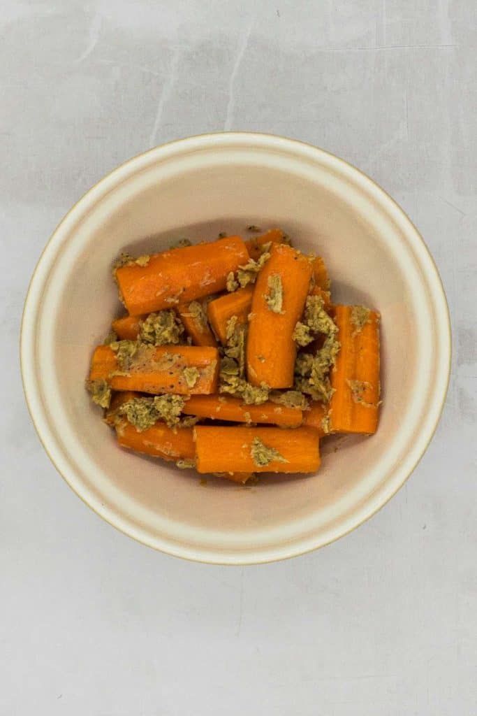 Carrots in a mixing bowl with the ingredients over them.