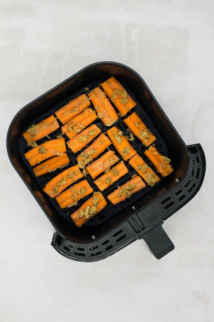 Uncooked maple carrots in an air fryer basket.