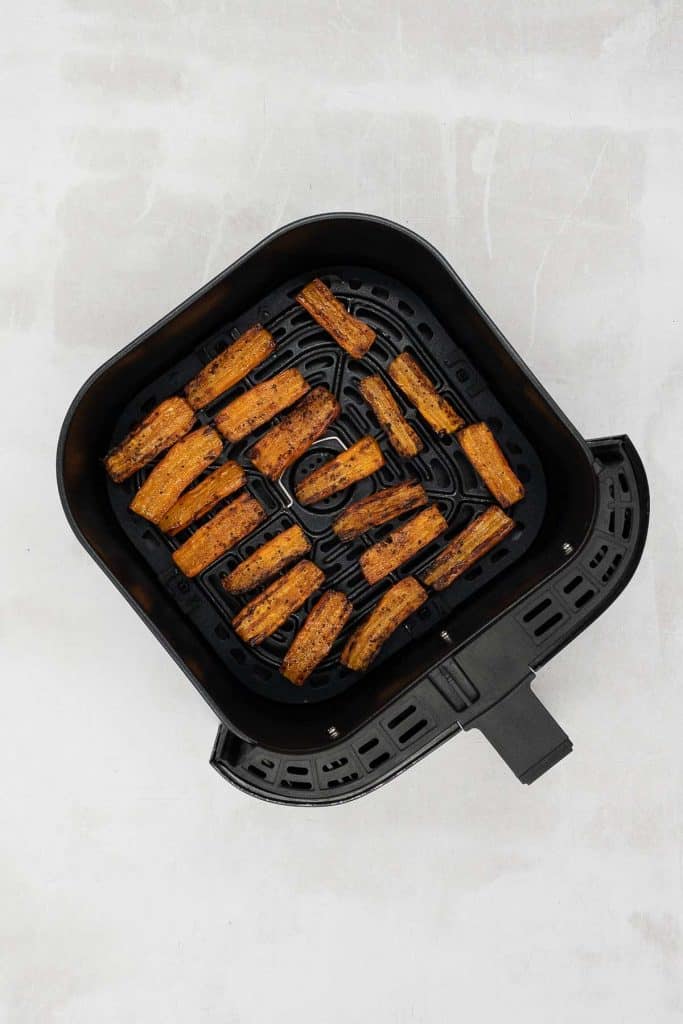 Cooked maple glazed carrots in an air fryer basket.