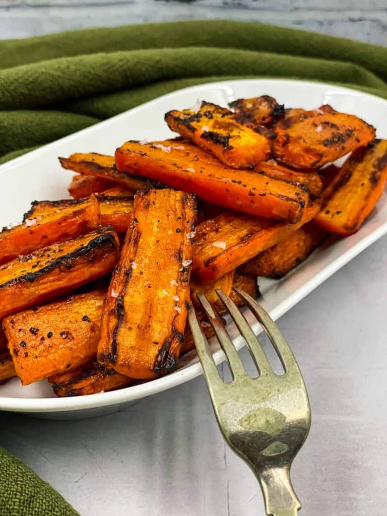 Air fryer maple roasted carrots in a serving plate with a fork.