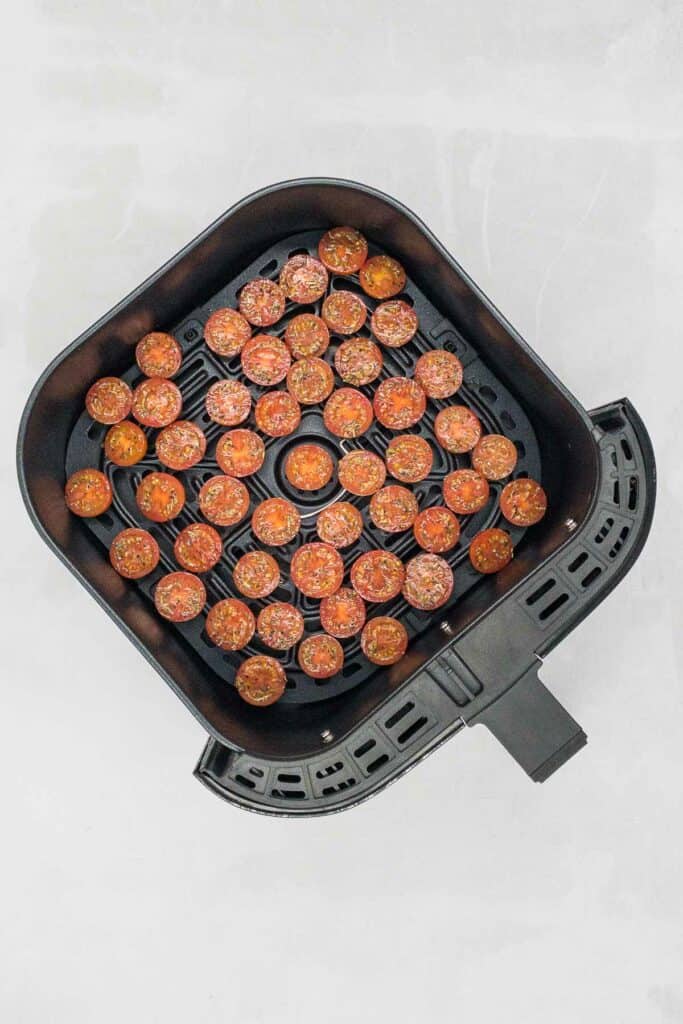 Cherry tomatoes in an air fryer basket.