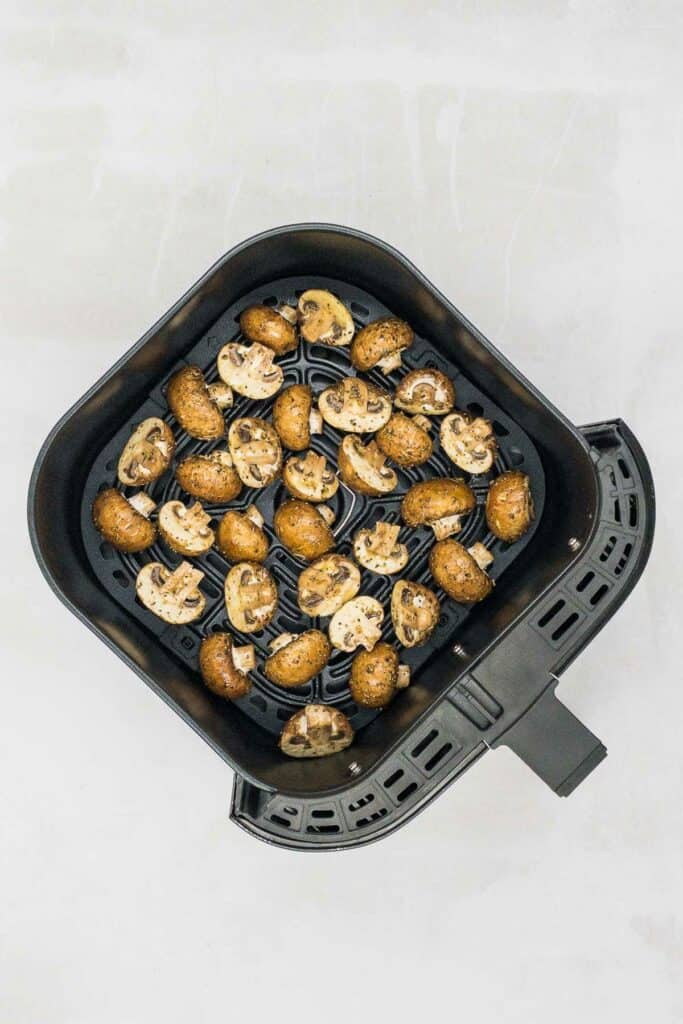 Mushrooms in an air fryer basket ready to cook.