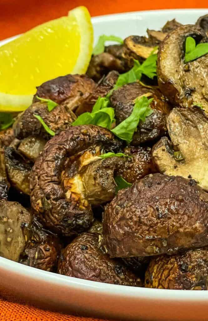 Delicious air fryer mushrooms in a bowl with a lemon wedge.