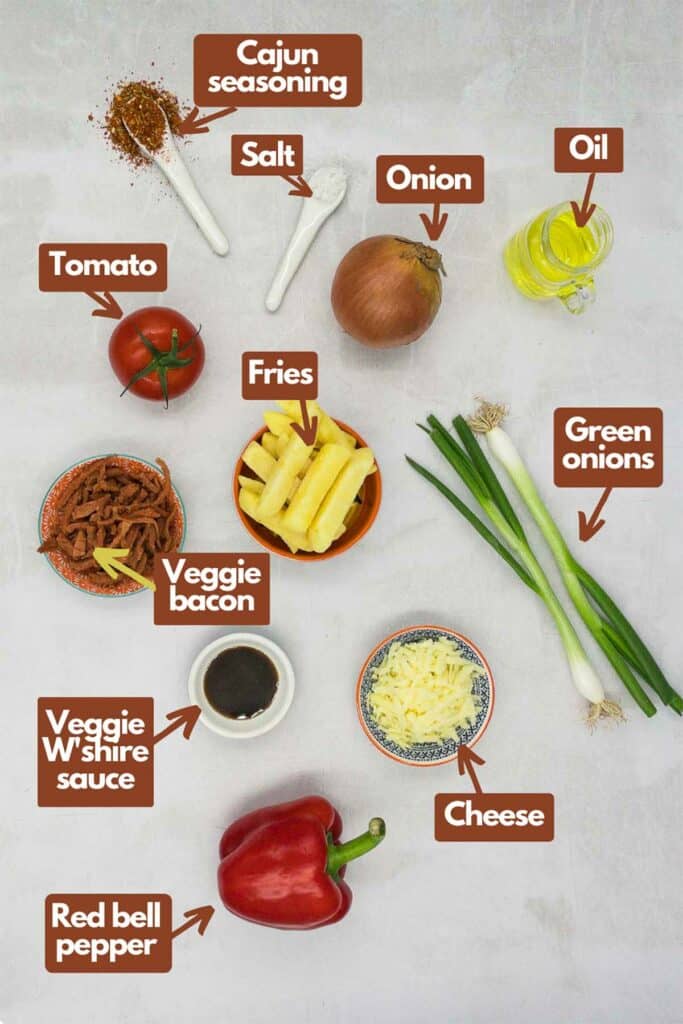 Ingredients needed, cajun seasoning, kosher salt, onion, olive oil, green onions, French fries, tomato, veggie bacon, veggie Worcestershire sauce, cheese, and red bell pepper.