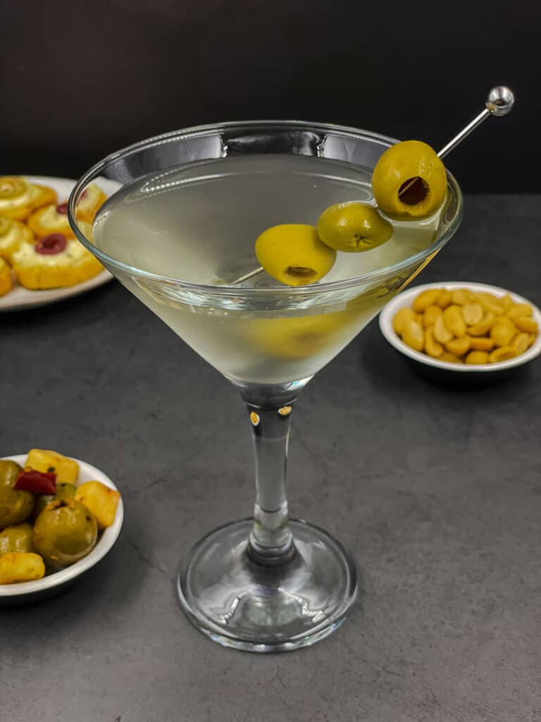 Dirty martini drink in a cocktail glass with olives.
