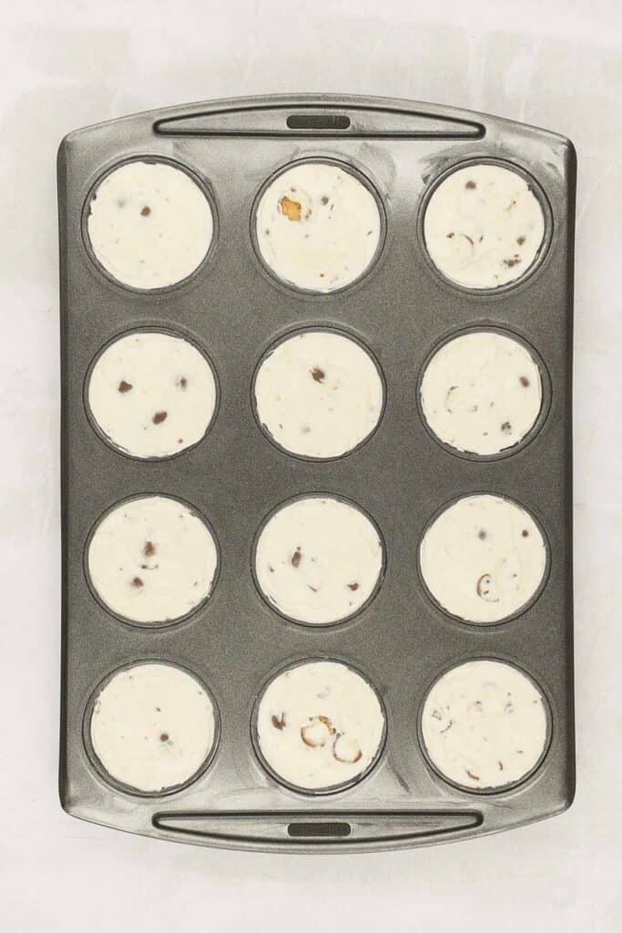 Muffin tin with cheesecakes in each hole.