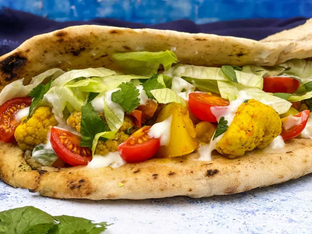 A naanwich filled with aloo gobi, lettuce, raita and tomato.