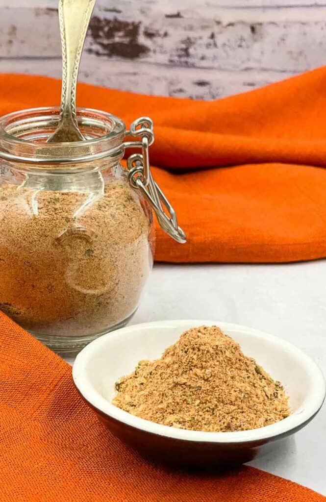 A jar of peri peri seasoning and a small dish with the spice mix in.