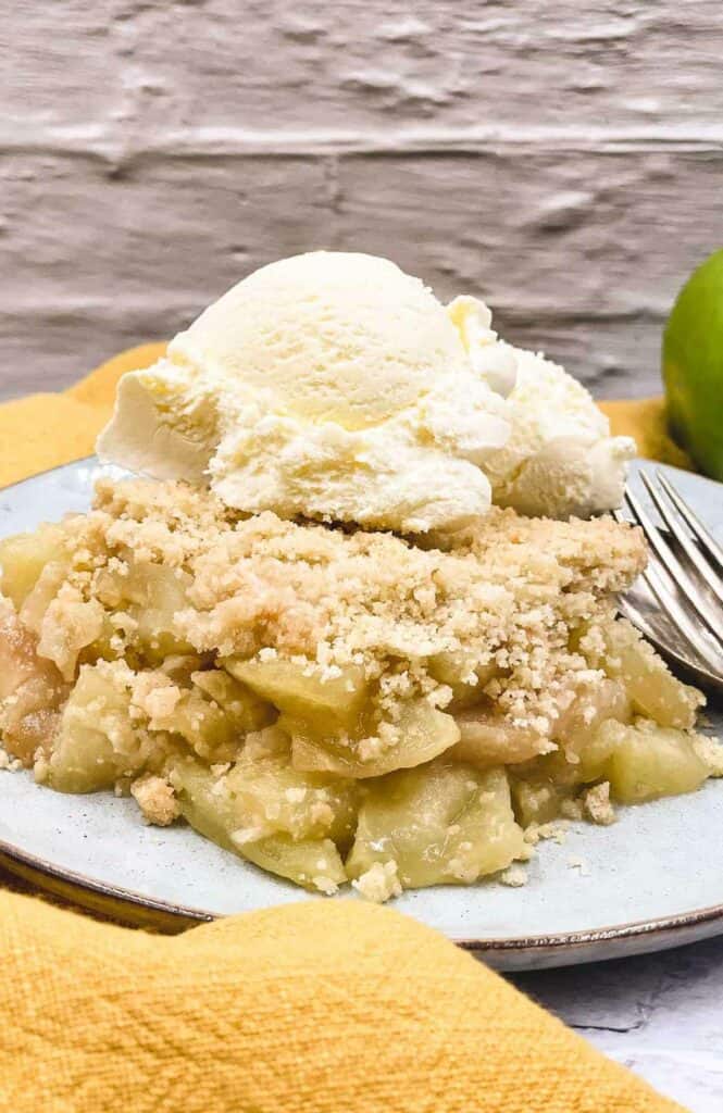 Vegan apple crumble on a plate with non dairy ice cream on top.