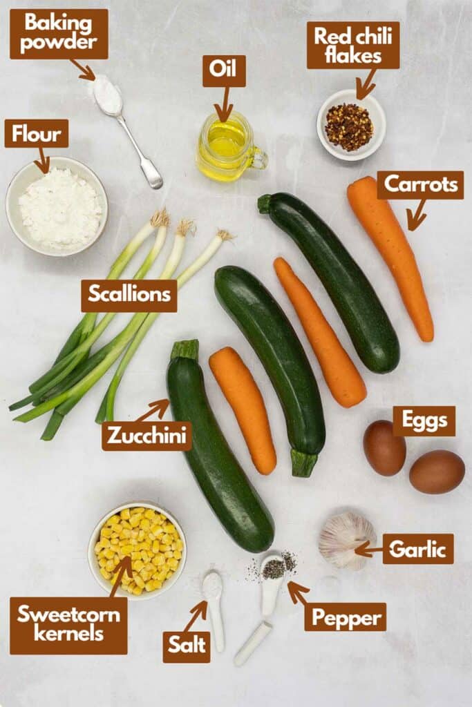 Ingredients needed, flour, baking powder, vegetable oil, red chili flakes, carrots, zucchini, scallions, eggs, garlic, salt, pepper, sweetcorn.