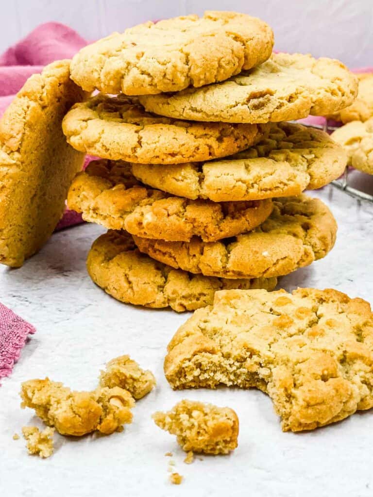 A stack of peanut butter cookies, with one cookie with a bite out of it.