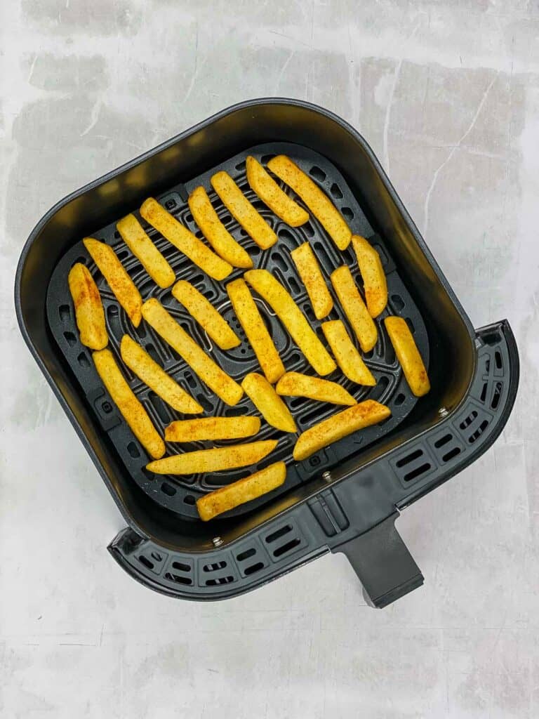 French fries cooked in Cayenne pepper in an air fryer basket.