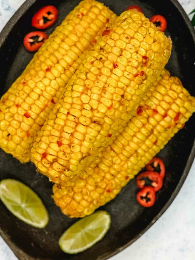 Three chilie lime corn on the cobs with wedges.