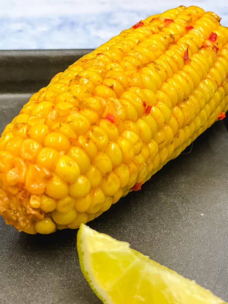 Chili and lime corn on the cob with a lime wedge.