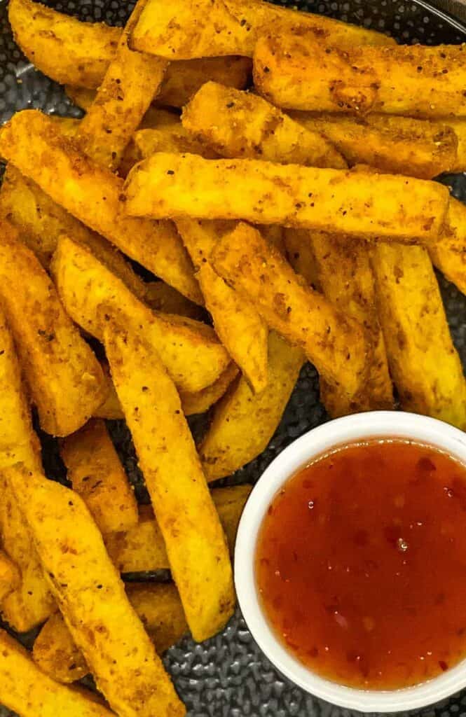 Delicious masala fries on a plate with chili sauce.