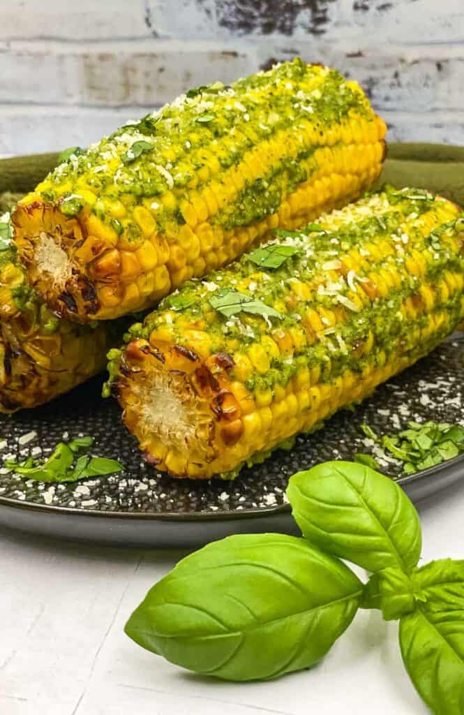 Corn on the cob with pesto butter on a plate.