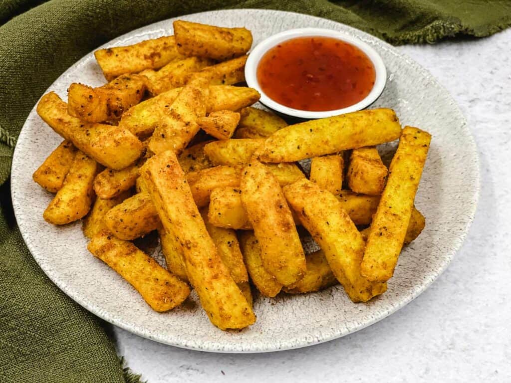 A bowl of delicious masala fries and a dipping sauce.