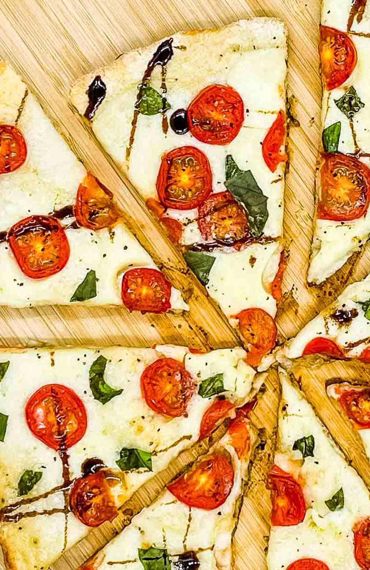 Slices of Caprese pizza on a wooden serving board.