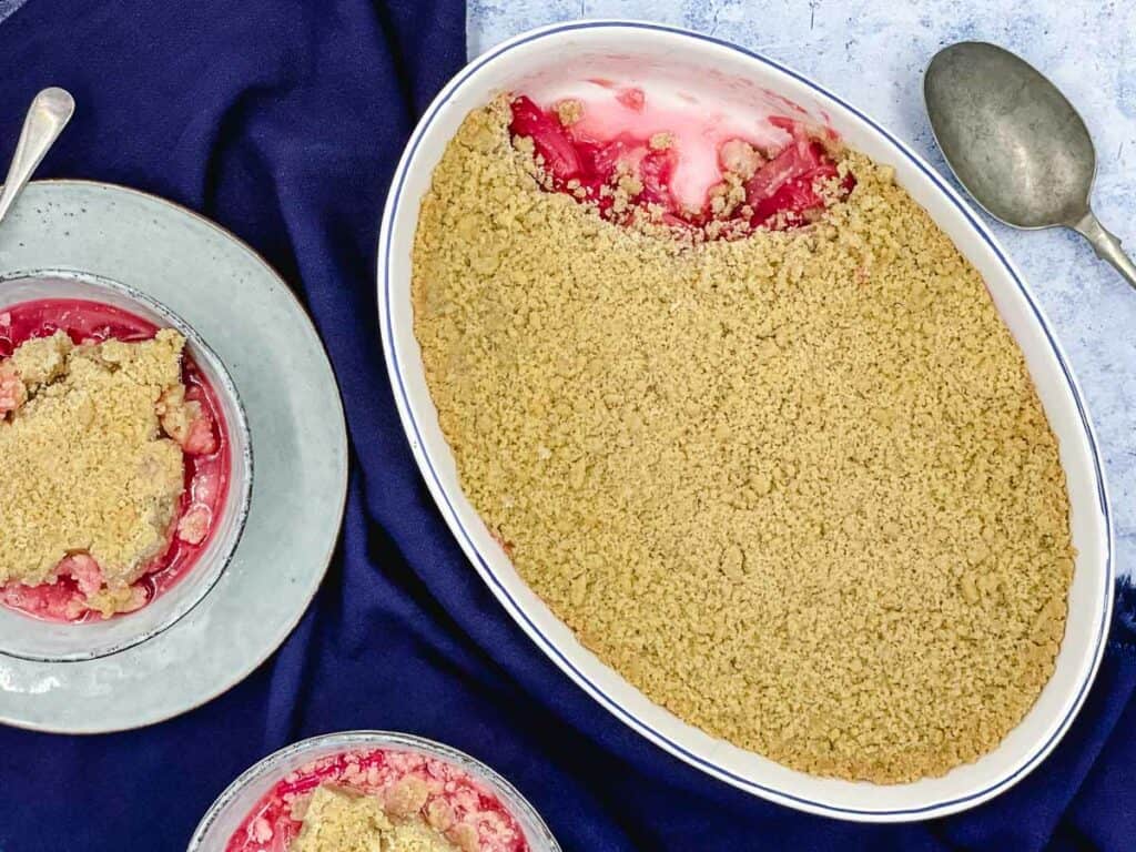 A dish of rhubarb crumble with a spoonful taken.