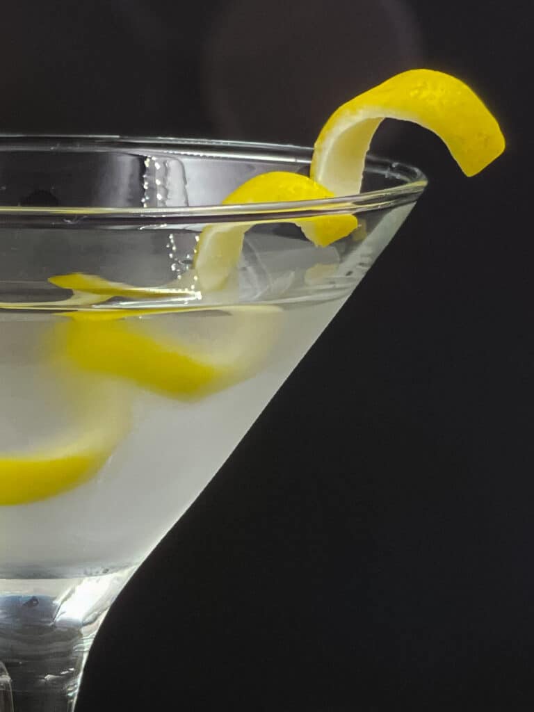 Half a glass of vesper martini with a lemon twist.