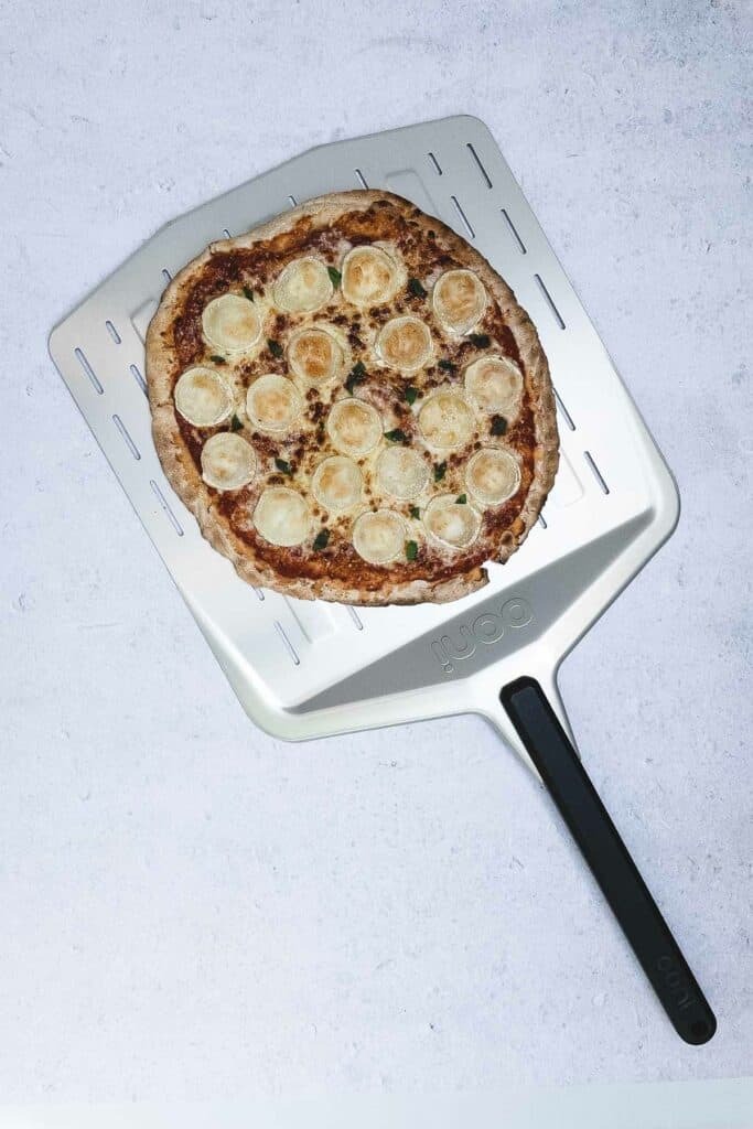 Cheese pizza on a pizza paddle just cooked.