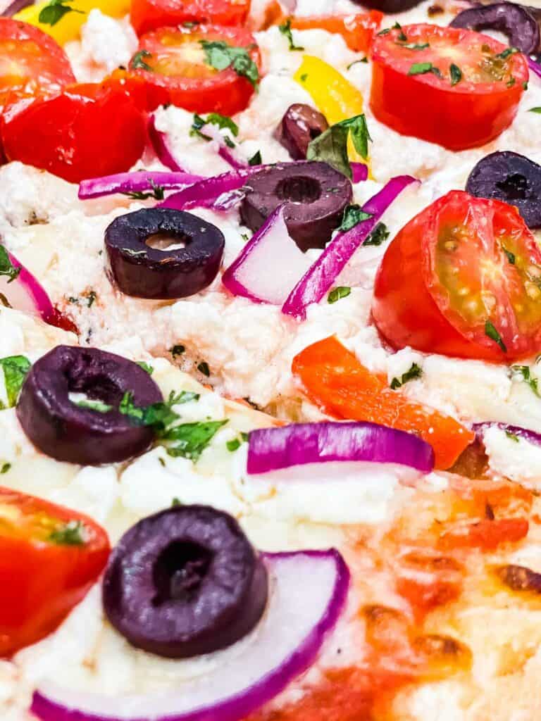 Greek pizza with feta, olives, tomatoes, and red onion.