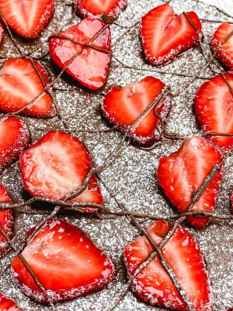 Strawberry slices on Nutella, with powdered sugar and Nutella drizzled over.