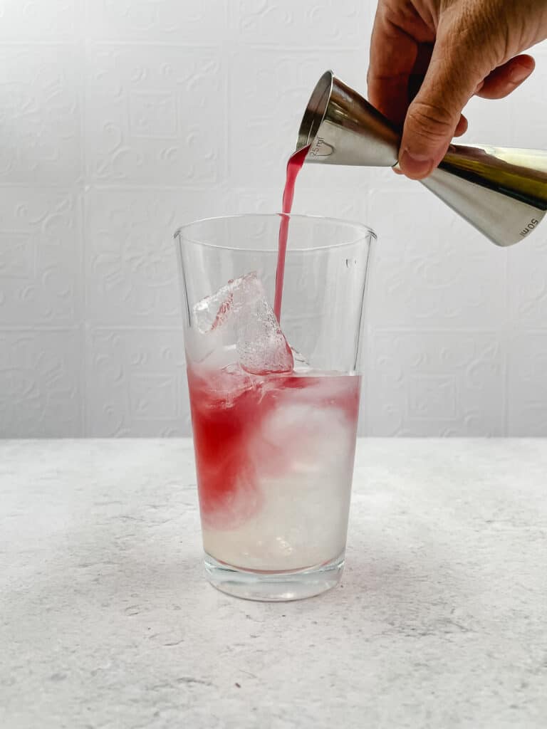 Adding cranberry juice to the shaker.