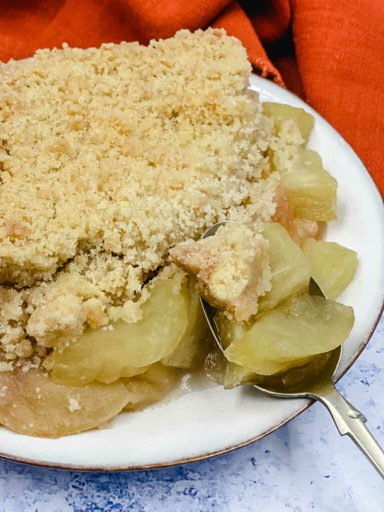 A plate of delicious gluten free apple crumble and a spoon full of it.