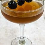A glass of Manhattan cocktail with cherries.