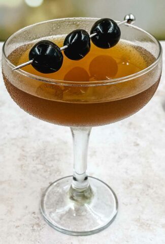 A glass of Manhattan cocktail with cherries.