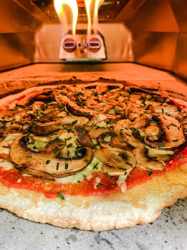 mushroom pizza cooking in a pizza oven.