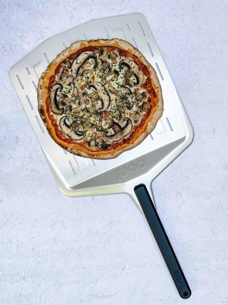 A cooked mushroom pizza on a pizza peel.