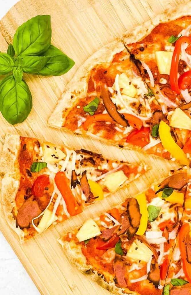 A homemade pineapple pizza sliced and ready to eat.